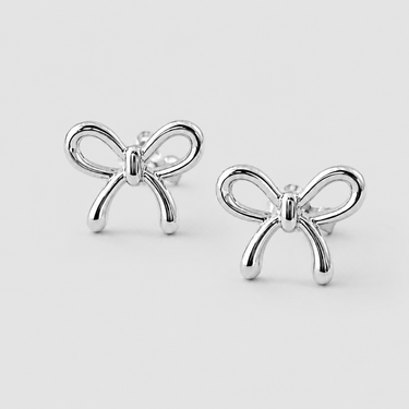 Silver Bow Stud Earrings in polished silver with delicate open-loop bow design, rounded ribbon ends, and shiny mirror finish on a light gray studio background.