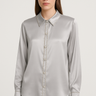 Model wearing the Soho Blouse in gray — satin-finish fabric, button-down front, long sleeves, pointed collar, elegant minimalist style.