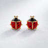 Solma Stud Earrings close-up showing red enamel ladybug design with black dot detailing and gold accents on light neutral background with soft shadow