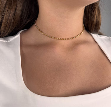 Model wearing Starla gold beaded necklace on white top