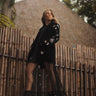 Woman wearing black velvet Starry Night Jacket with embroidered silver stars, standing outdoors.