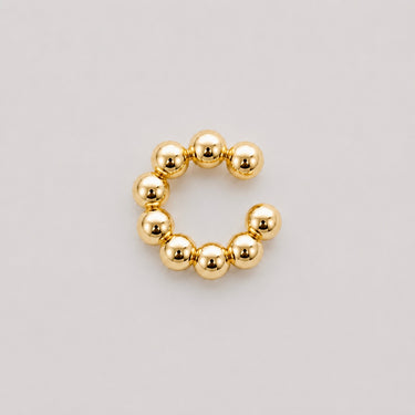 Stelle Ear Cuff in polished gold featuring rounded bubble beads in a modern open cuff silhouette, designed as a playful statement ear cuff with a sleek high-shine finish on a soft neutral background.