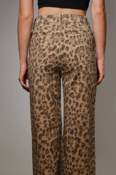 High-rise leopard-print jeans with subtle studded accents and wide-leg silhouette, photographed in soft natural light on a neutral background, back view.