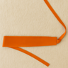 Tangerine wrap belt displayed flat on beige linen background.