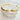 A gold-colored bracelet cuff with spike details and small embellishments, displayed on a white cushion.