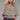 Model wearing neutral knit cape cardigan with oversized buttons and textured fabric, front view.
