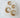 Pair of gold Tora huggie earrings on a white cushion