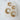 Pair of gold Tora huggie earrings on a white cushion
