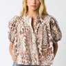 Tyrath Blouse leopard print blouse with puff sleeves and button-front design, featuring a relaxed airy fit and neutral animal print, styled with blue denim on model against white studio background.