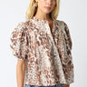 Tyrath Blouse animal print puff sleeve blouse shown from angled front view, highlighting dramatic sleeves, soft drape, and polished button-front styling paired with casual denim.