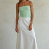 Woman wearing a strapless green top and white skirt against a plain background