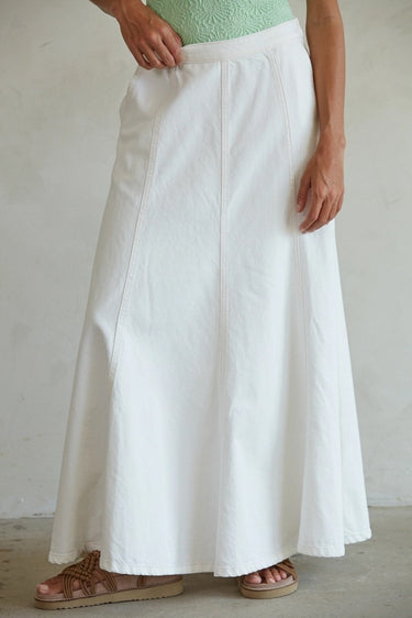 Person wearing a white skirt with a plain background