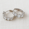 Velluto Huggie Earrings, silver huggie hoop earrings with baguette-cut crystal design and polished mirror finish, photographed on white linen background with soft editorial lighting.