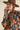 Close-up of model wearing navy knit sweater with bold orange and pink floral knit design.