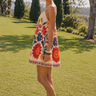 Model wearing the Aitana Jumpsuit in a colorful floral print with adjustable straps and a relaxed fit, shown in a side profile outdoors to highlight the lightweight silhouette and vacation-ready style.