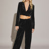 A female model wearing a black Akima pant with a high waist and relaxed fit. The model is paired with a cropped top and white sneakers, standing against a neutral background.