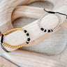 Two bracelets laid on a wooden surface, one with gold-colored beads and the other with black and white beads, showcasing their intricate designs by Matte