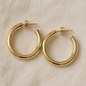 Gold classic polished hoop earrings on white linen backdrop, Almudena Hoop Earrings.
