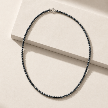 Amelty Necklace close-up of dark faceted beaded necklace on neutral background showing delicate bead details.