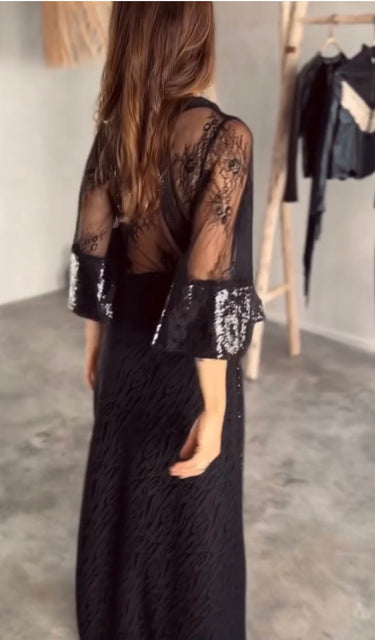 Woman wearing sheer black Ammica Maxi Dress with beaded details indoors under soft light.
