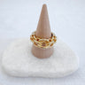 A gold-plated chunky chain ring displayed on a beige cone with a white base.