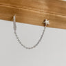 Arianna chain huggie stud earring in gold plated star design with delicate connecting chain on wood and light background