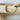 A gold-colored bracelet with a mix of solid and patterned beads displayed on a wooden surface by Matte