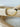 A gold-colored bracelet with a mix of solid and patterned beads displayed on a wooden surface by Matte