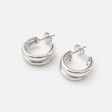 Artsy Hoop Earrings featuring polished silver-plated double-band hoop earrings with a sculptural layered design, rounded high-shine finish, lightweight construction, secure post-back closure, and a bold contemporary silhouette.