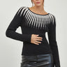 Woman wearing a black ribbed knit sweater with white contrast neckline, long sleeves, and slim fit — Aurora Sweater by Matte.
