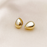 Aurore Huggie Earrings, gold domed huggie hoop earrings with smooth rounded silhouette and polished mirror finish, photographed on white linen background with soft editorial lighting.