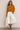Banana Bloom Crochet Top yellow long sleeve crochet knit top worn with white skirt, showing relaxed fit and bold banana pattern.