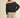 Woman wearing the Barranquilla Sweater off one shoulder in black, back view