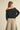 Woman wearing the Barranquilla Sweater off one shoulder in black, back view