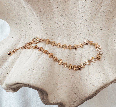 Caeli gold bracelet displayed on textured seashell surface