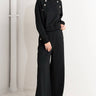 Woman wearing black pants with button details on a white background 