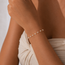 Model wearing the Carroll Bracelet featuring delicate heart-shaped pearls on a fine gold chain.