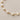 Carroll Bracelet with heart-shaped pearl accents on a delicate gold chain against a neutral background.