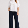 Woman wearing the Castca white floral appliqué top with dark wide-leg pants, front view.