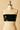 Cena Bandeau — black glossy strapless vinyl bandeau top displayed on mannequin against beige background, minimalist night-out piece.