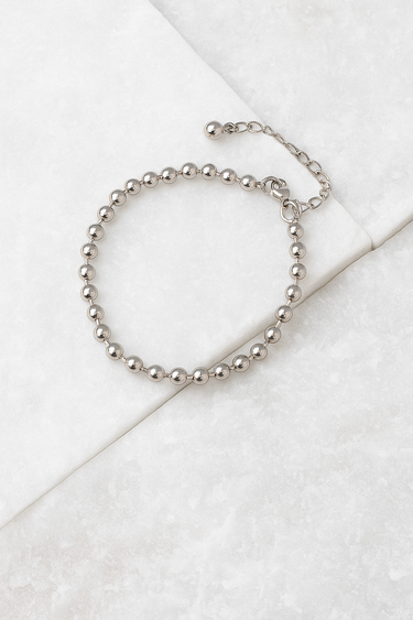 Silver beaded anklet on a white surface