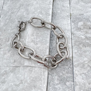 Chunky silver chain bracelet by Matte displayed on light grey stone background