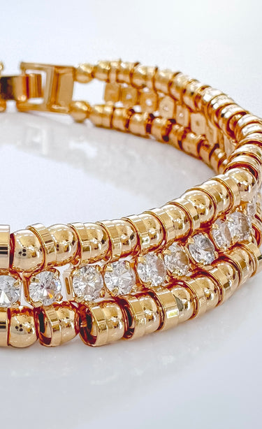 Close-up of gold double row bracelet showing polished beads and sparkling cubic zirconia stones