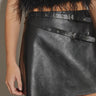 Black faux leather mini skirt with buckle waist detail styled with ankle boots — night-out look.
