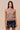Clotet Top sleeveless neutral crochet-style top worn with black ruffle shorts, showing open-knit texture, straight fit, and fringe hem.