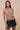 Clotet Top front view highlighting breathable open-knit fabric, soft taupe color, and subtle boho fringe detail.