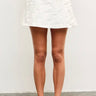 Model wearing white textured floral mini skirt with sneakers — modern and feminine summer look, front view.