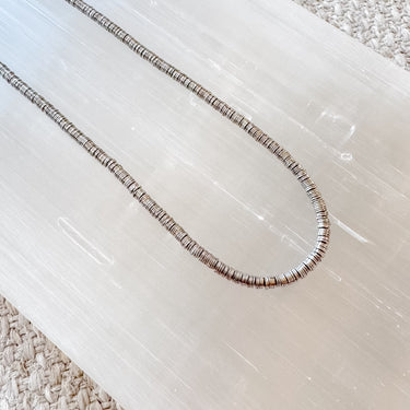 A gold-filled disc beaded necklace laid out on a surface, showcasing its layered and textured design.