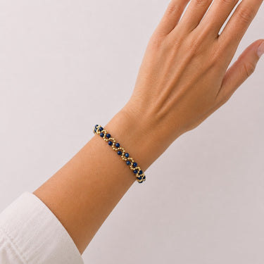 Model wearing the Efi Bracelet in navy blue and gold with polished metallic beads on an adjustable chain.