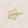Gold star-shaped hair clip with pearls on a beige background